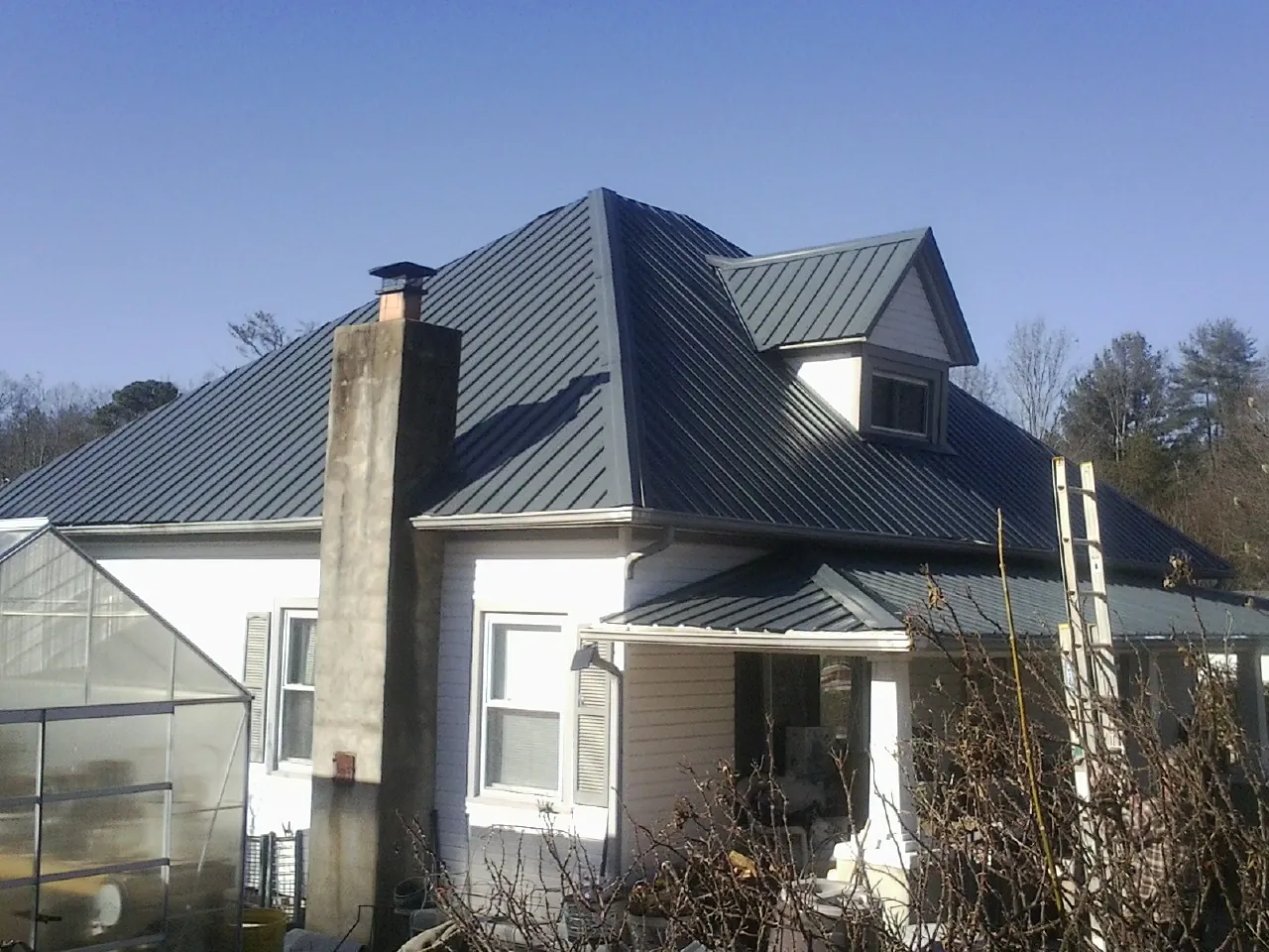 Dark blue standing seam metal roof on a white farmhouse with dormer — Slate & Tile Roof Repair by Roofing Brothers in Baconton