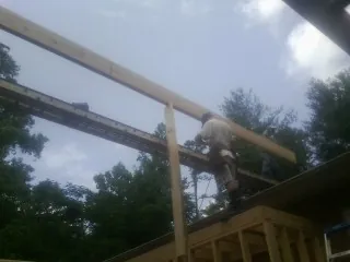 Carpenter setting a ridge beam over a new addition frame — Ice Dam Removal by Roofing Brothers in Baconton
