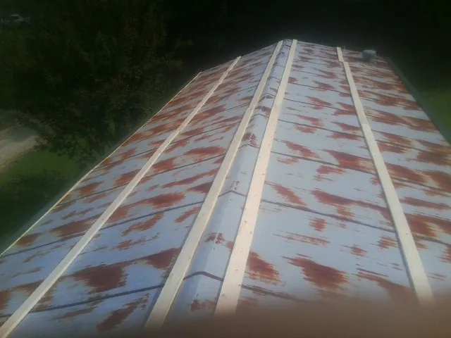 Rusted metal roof panels with new wood purlins before replacement — Storm Damage Roof Repair in Baconton by Roofing Brothers