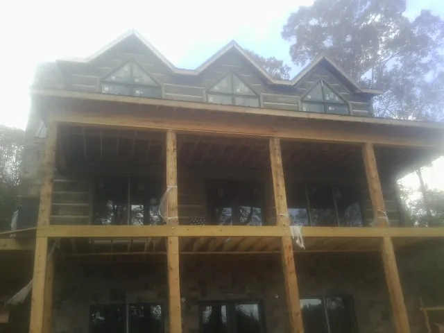 Dormers and porch framing on a large log home under construction — Roof Coating work by our crew in Baconton