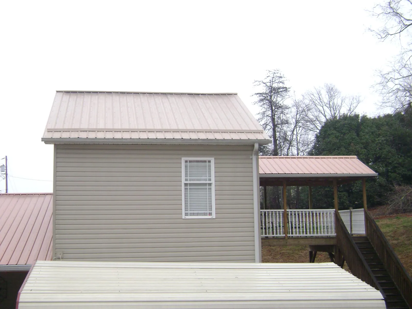 Tan metal roofs on a two story addition and attached porch, from a Roof Replacement job in Baconton