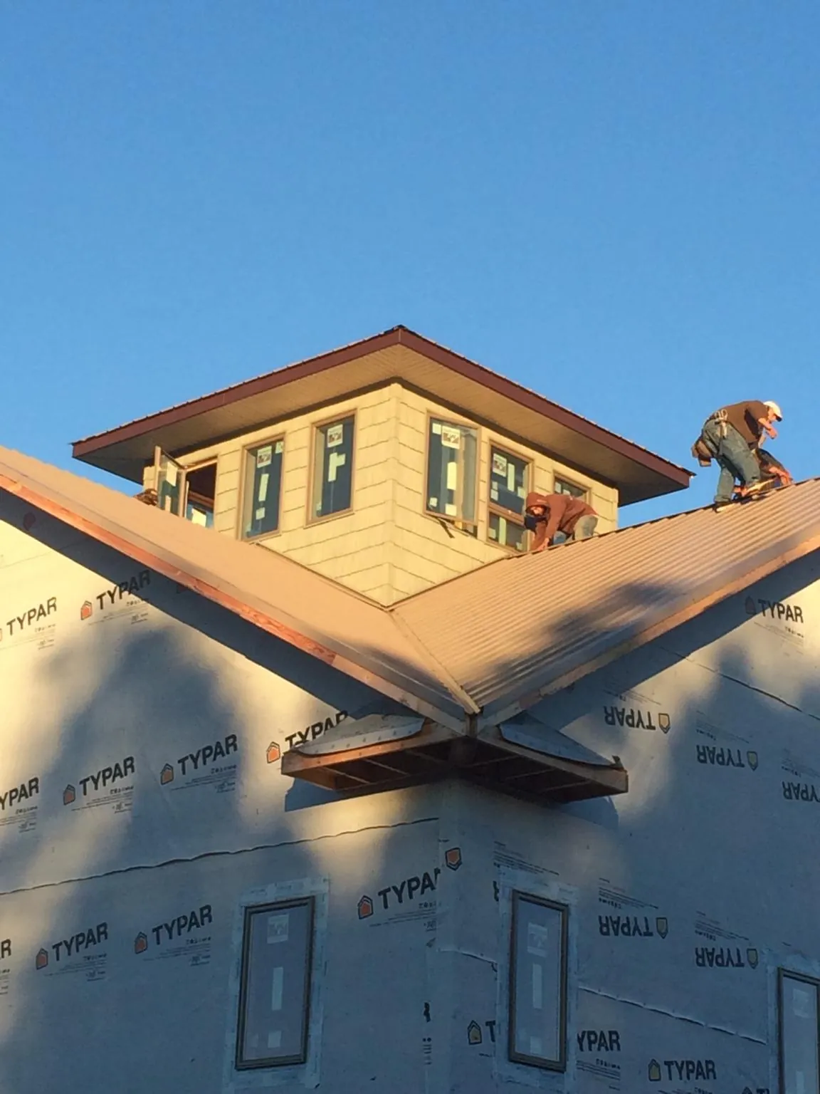 Roofers working around a rooftop cupola on a new metal roof at sunset — Roof Waterproofing in Baconton by Roofing Brothers